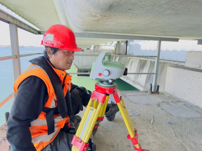Landmeter van Kawthoolei stelt een totalstation op onder een brugdek