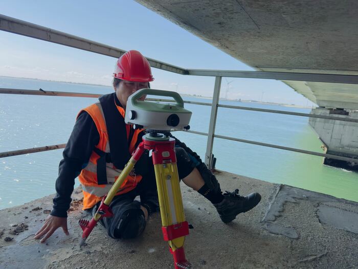 Landmeter stelt een instrument op bij een waterkering