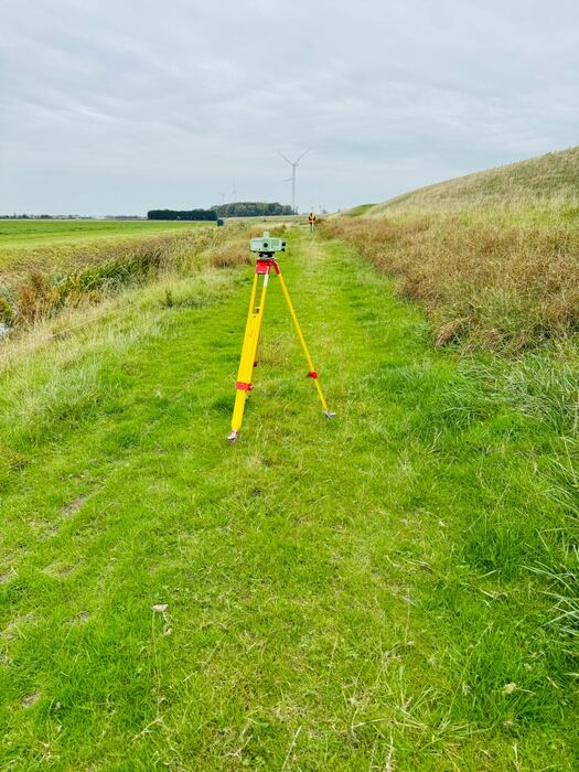 Waterpasinstrument op statief op een grasdijk